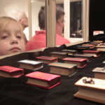 Child looking at miniature books in glass case