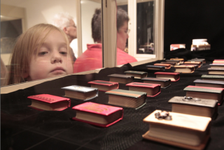 Child looking at miniature books in glass case