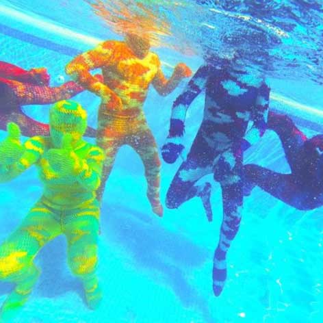 People in crocheted Olek bodysuits swimming underwater