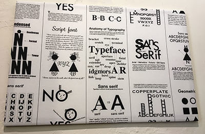 Framed piece of fabric with names and descriptions of fonts