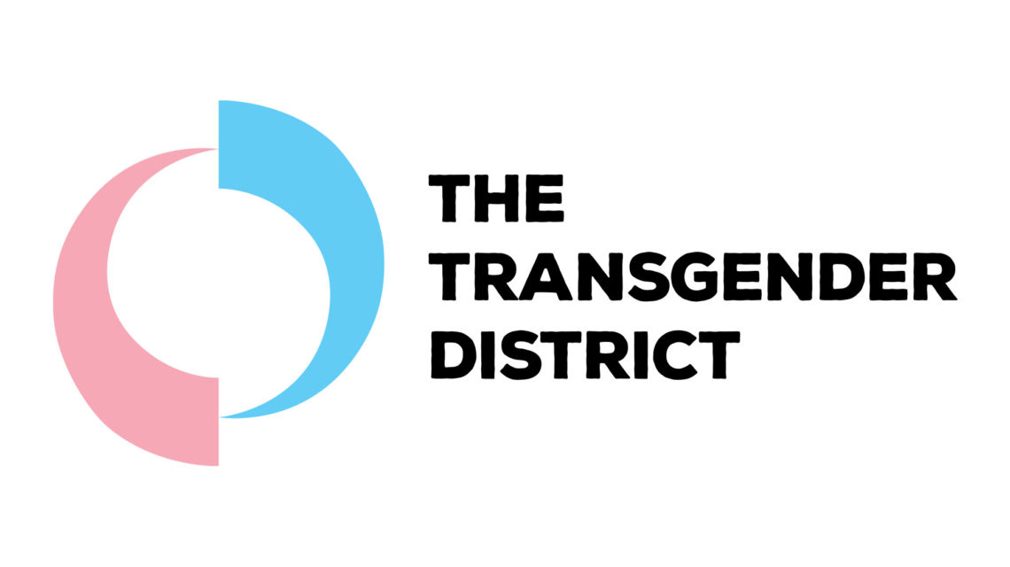 District logo. Two fat arrows swirling around a center point. The left arrow points up and the pink of the transgender flag. The right arrow points down and is the light blue of the transgender flag. To the right of the arrows is heavy, black, sans serif, all-caps type: "The Transgender District," on three lines. Type is centered vertically on arrows.