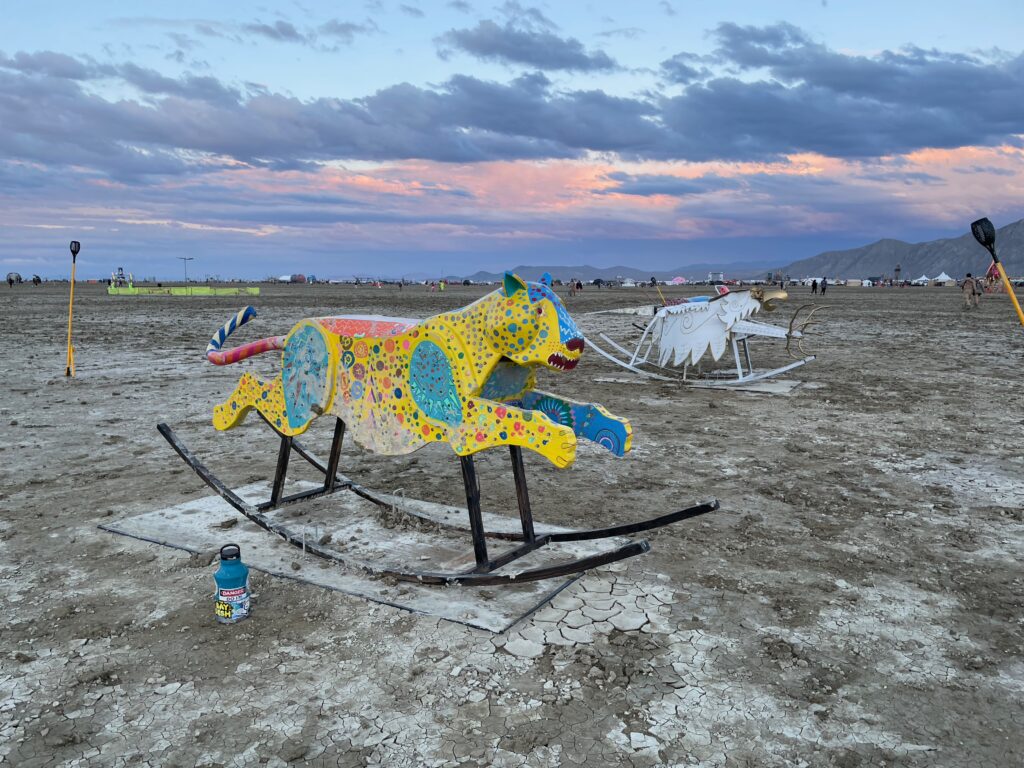 A rocking "horse" in the shape of a snarling yellow leopard with a blue face and multicolored stylized  spots. Slightly larger than human scale.