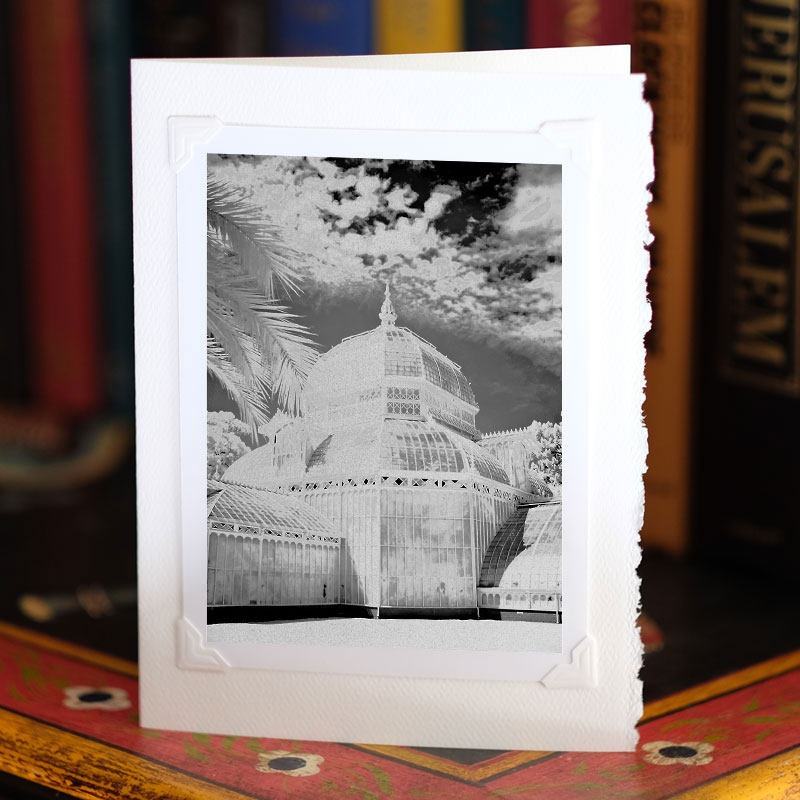 Photo of greeting card on a bookcase, standing up, with a photo attached to it with photo corners. Infrared photo of an elaborate greenhouse, the Conservatory of Flowers in San Francisco's Golden Gate Park.
