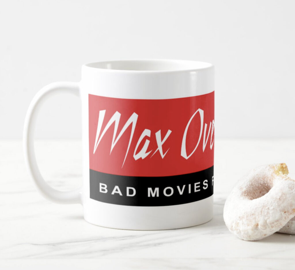 White ceramic mug with Max Overdrive Video logo, left view, on a marble counter. A powdered donut is partially visible to the  right.