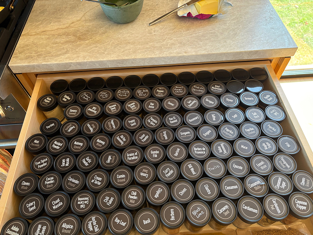 Open drawer with many  labeled spice jars