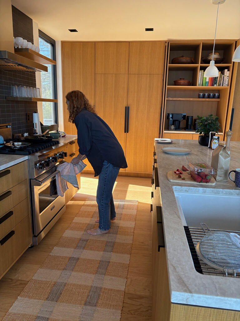 Red-headed woman leaning over the stove in a beautiful modern kitchen