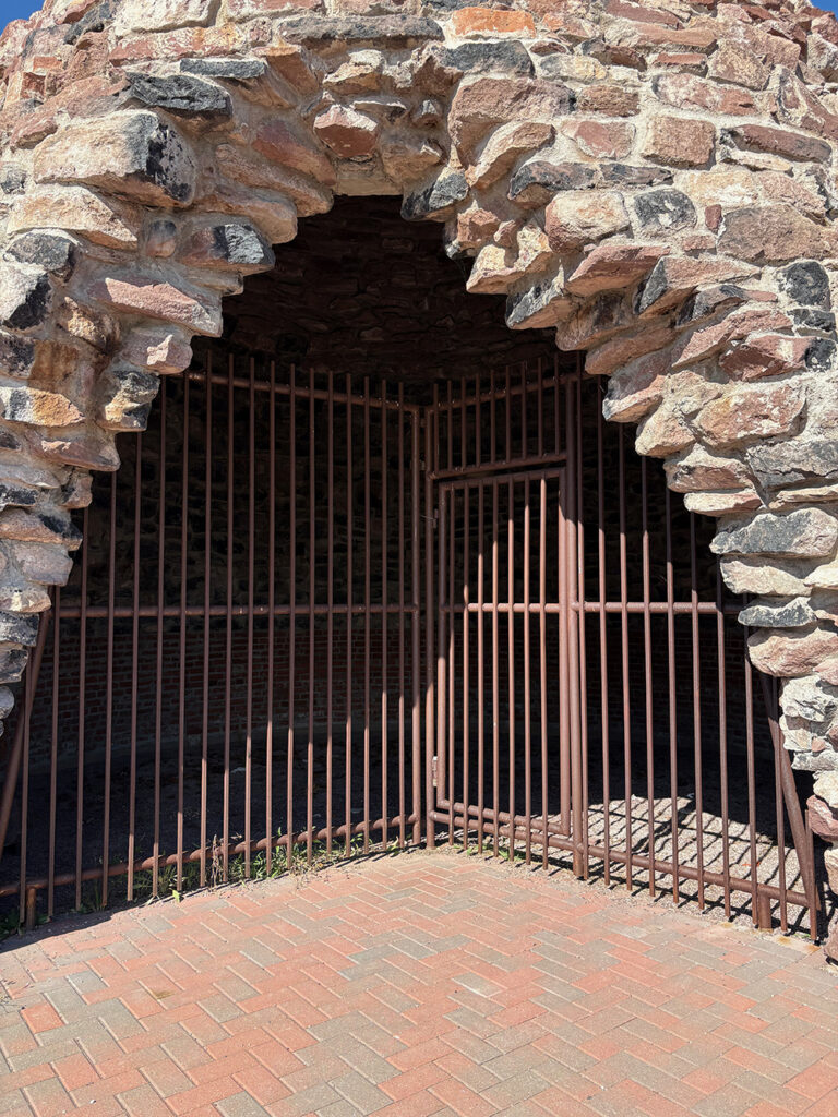 Doorway of beehive-shaped structure with iron grate preventing entry - closeup