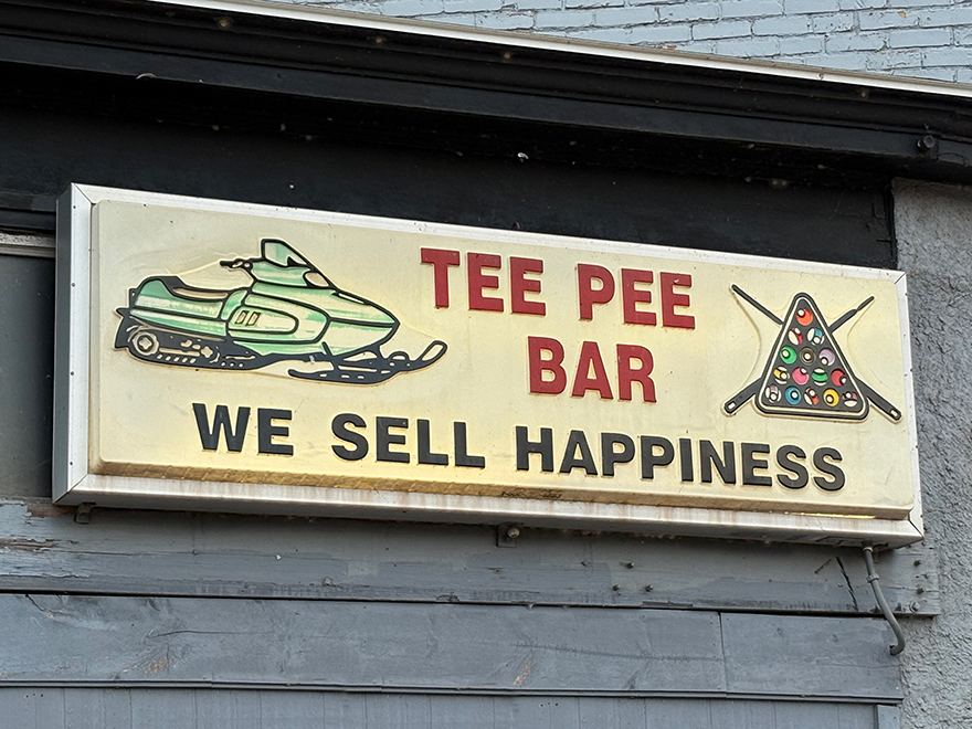 Illuminated sign on side of building: "TEE PEE BAR - WE SELL HAPPINESS"