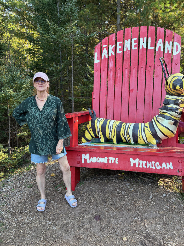 Big red chair with woman with red hair standing on front left.