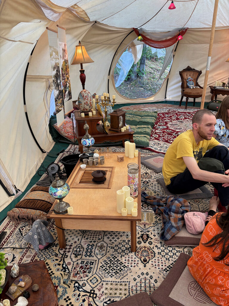 Interior of a large cream-colored canvas tent, with tea-making apparatus and supplies in the foreground