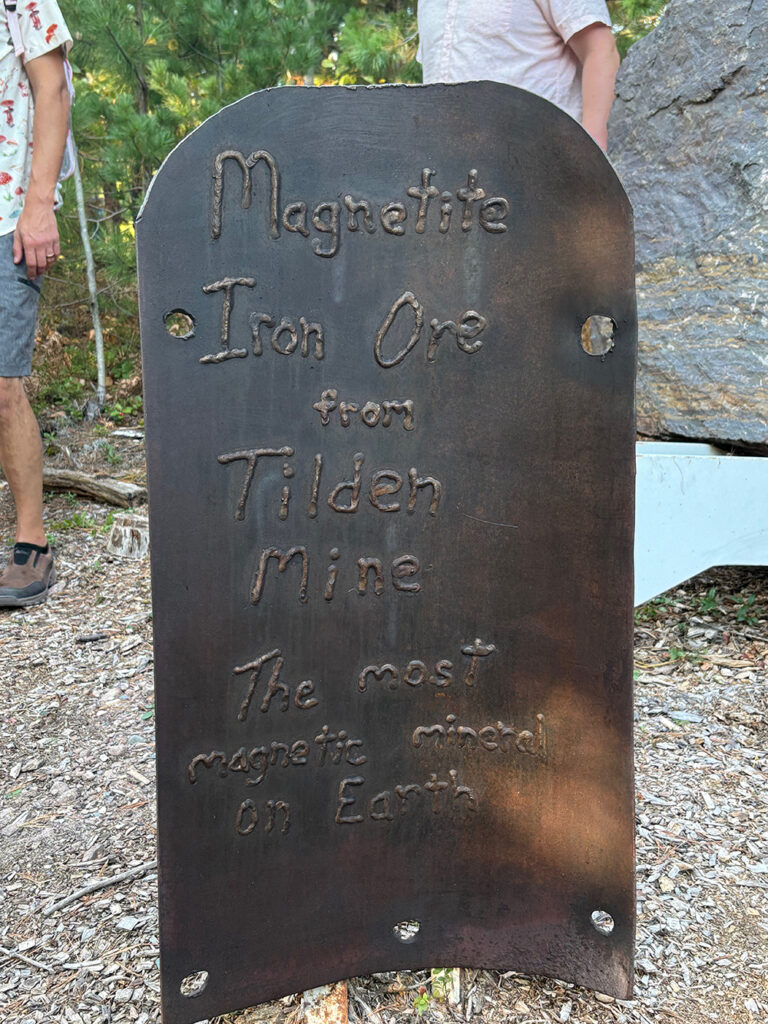 Upright sheet of metal with welds spelling out "Magnetite Iron Ore from Tilden Mine - the most magnetic mineral on Earth"