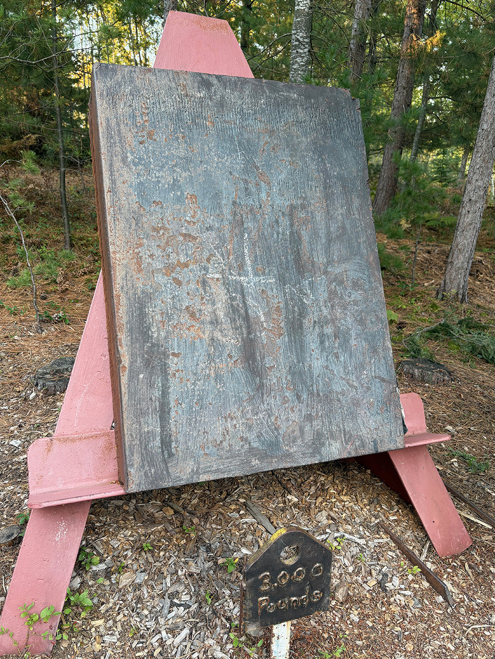 Huge steel slab on supports. Welds on sign in front spell out "3,000 Pounds."