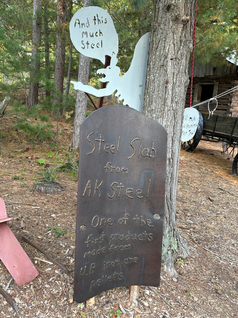Upright sheet of metal with welds spelling out "Steel slab from AK Steel - One of the first products made from U.P. iron ore pellets"