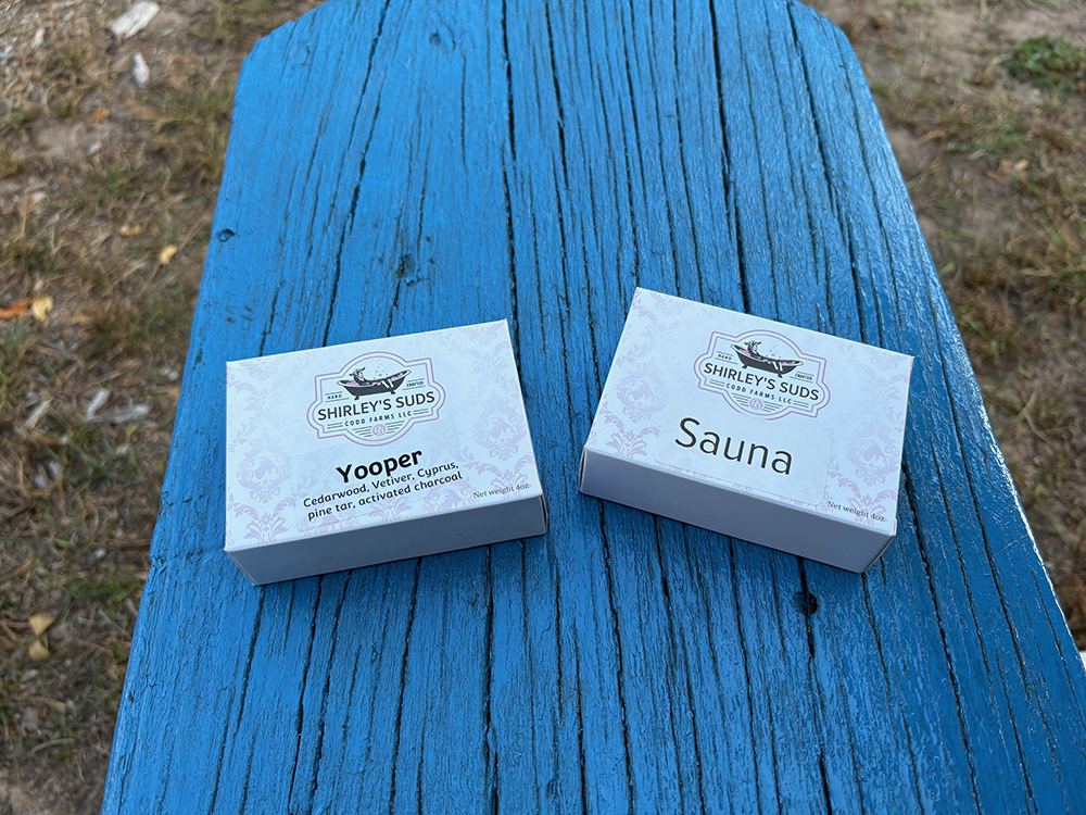Two white boxes of soap on a bright blue wooden bench. One is labeled "Yooper" and the other, "Sauna"